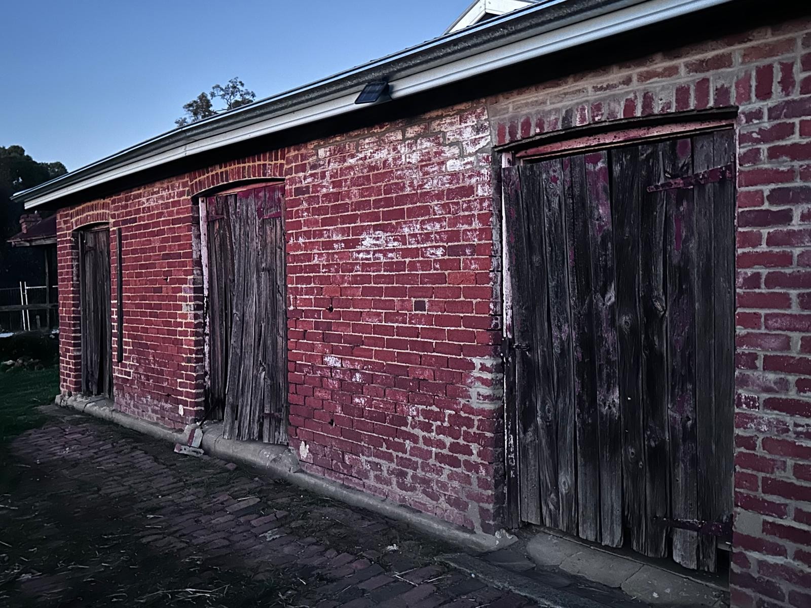 The dairy shed's red brick walls and original timber doors at Guildford Farm